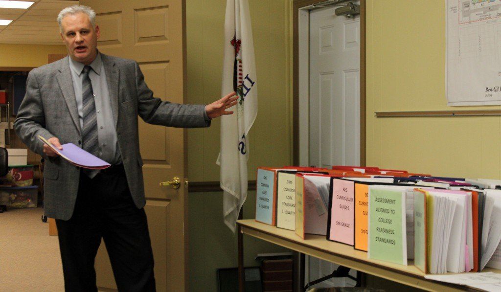 Joe Tieman stands next to all the current curriculum in place in the district. 