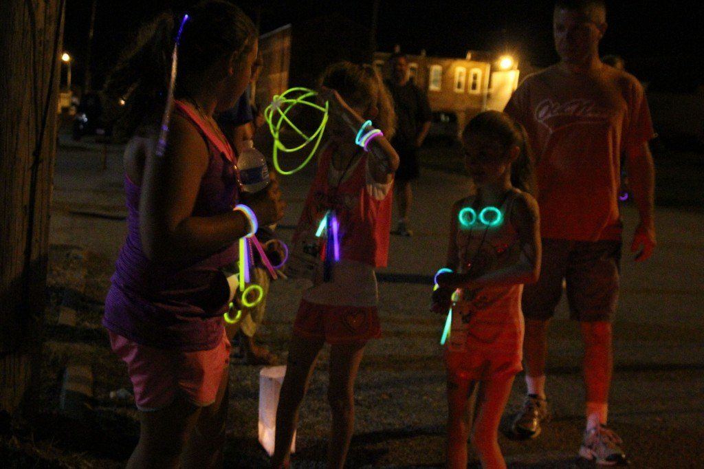 Youngsters decked in glowing bracelets and necklaces grab a water and talk about the route after they finish the 1-mile race.
