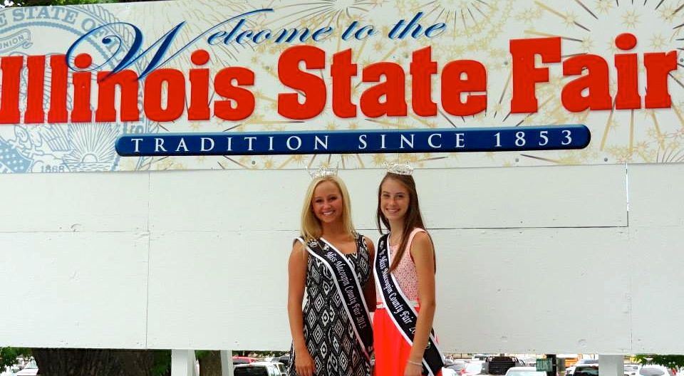 Kimmy Dworzynski, 2013 Miss Macoupin County, and Maya Marcacci, 2013 Jr. Miss Macoupin County, pose next to the Illinois State Fair sign this week. 