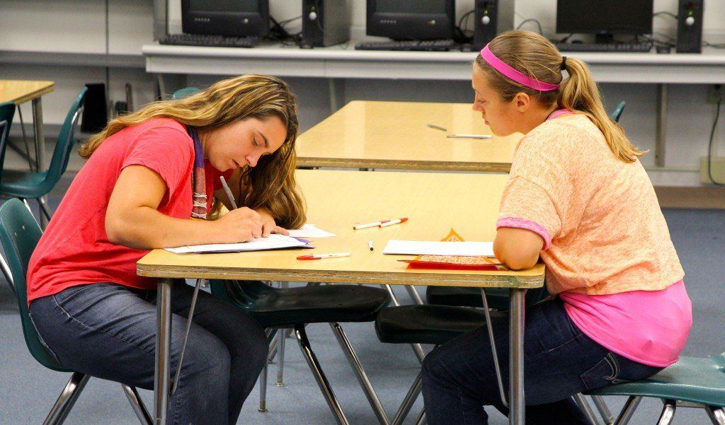 Students and parents fill out paperwork as they wait for their turn to go through the fees with the high school secretaries. 