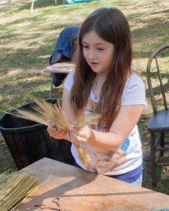Katie Egelhoff, 8 of Shipman, spreads out the bristles of a small whisk broom she just made during Fall Festival. Photo by Louise Jett, MCHS Public Relations Officer.