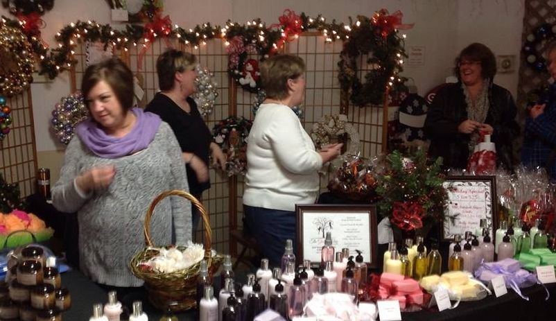 Customers browse soaps, candles, decorations, and other fine items at The Giving Tree's booth yesterday at the Holiday Market. 