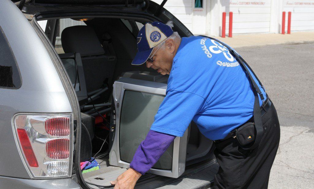 Alderman Mickey Robinson unloads a television from the back of a vehicle. 