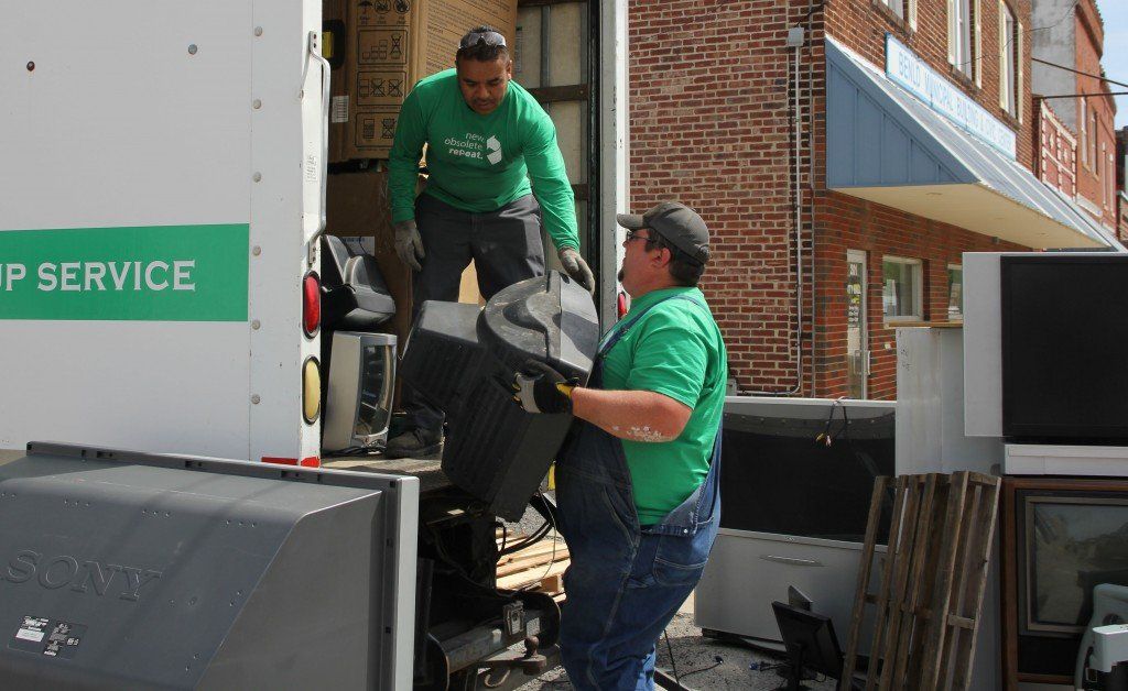 Workers from CJD E-recycling load a television into the truck. 