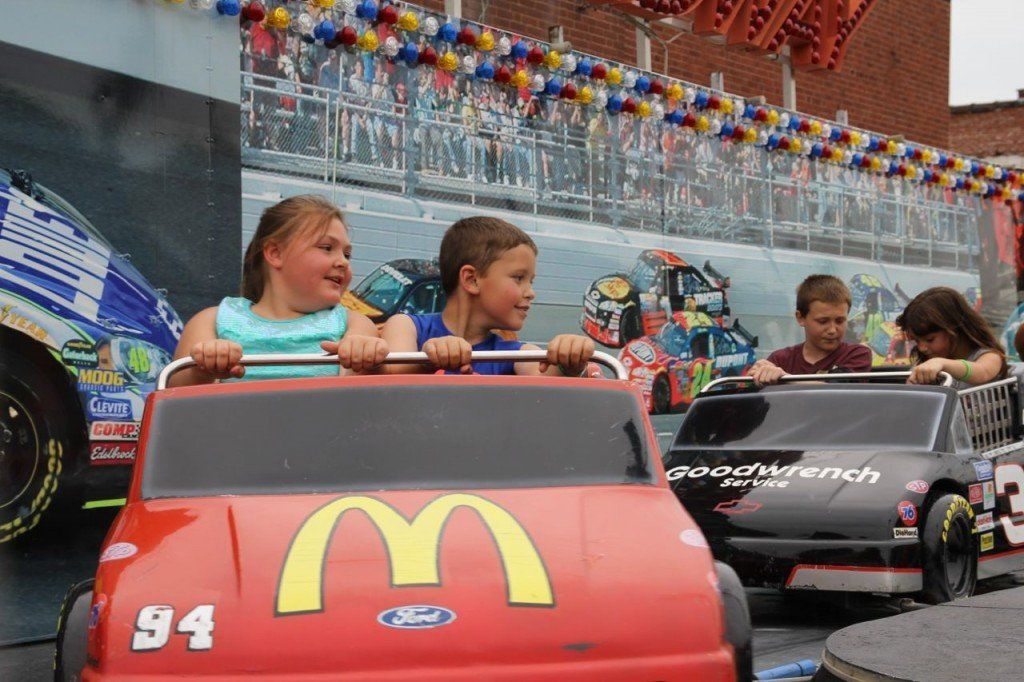 Children brace themselves as the Nascar ride swings abruptly. 