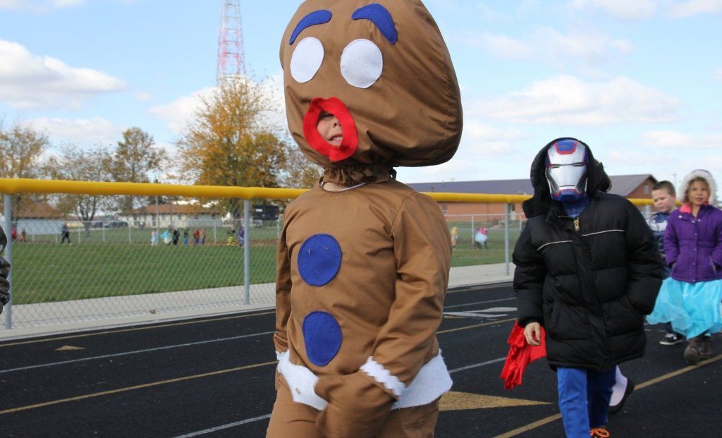 A student dressed as gingerbread man walks around the track in part of the elementary school's costume parade. 
