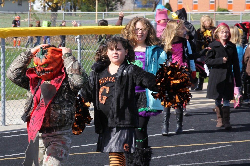 Students dressed in a variety of costumes stroll around the track for the elementary costume parade. 