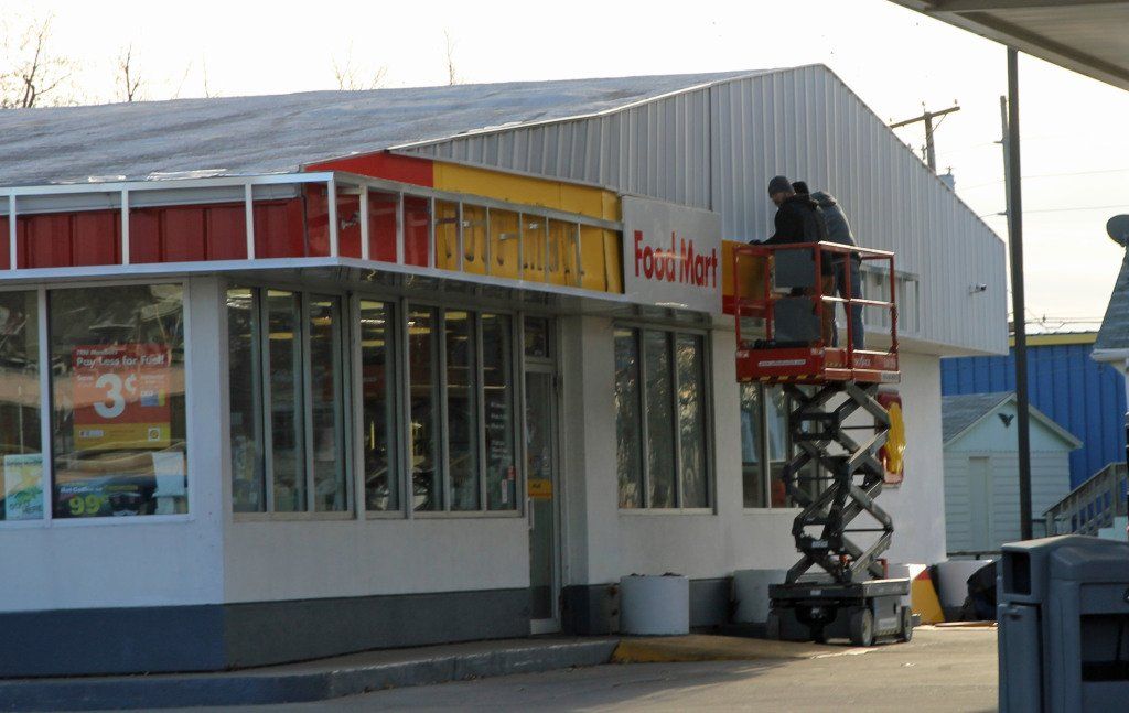 Workers install new signage at Gillespie's Shell Station yesterday. 