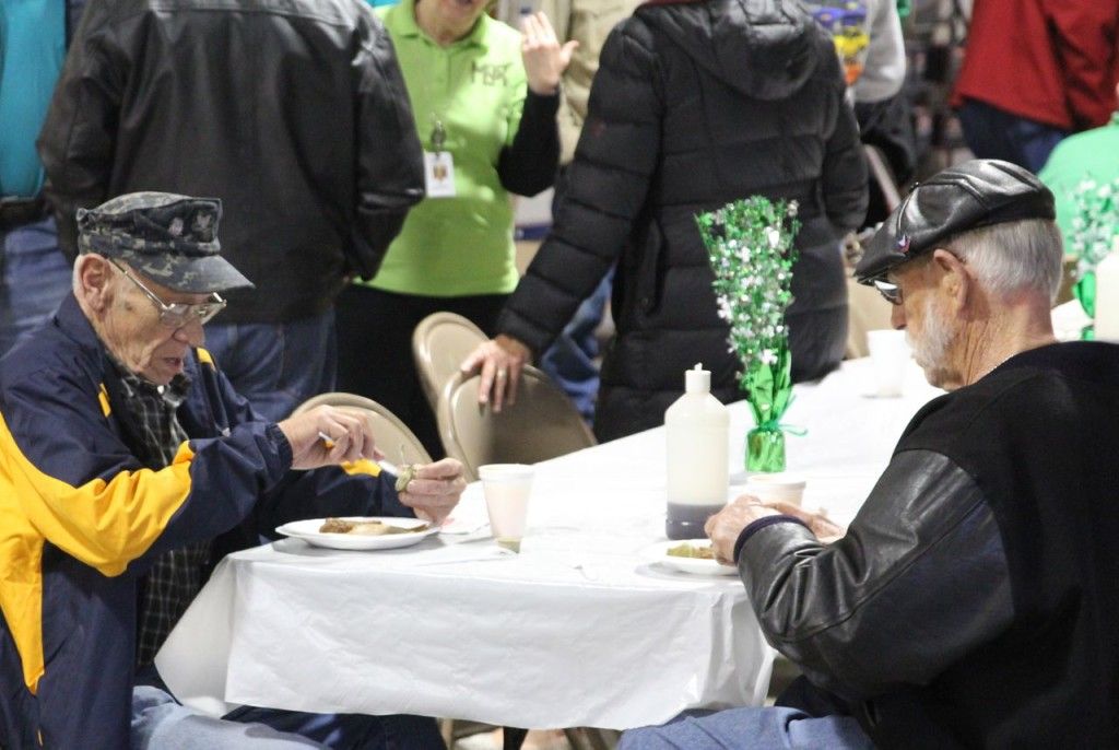 Customers fill their plates with pancakes and sausage while drinking juice. 