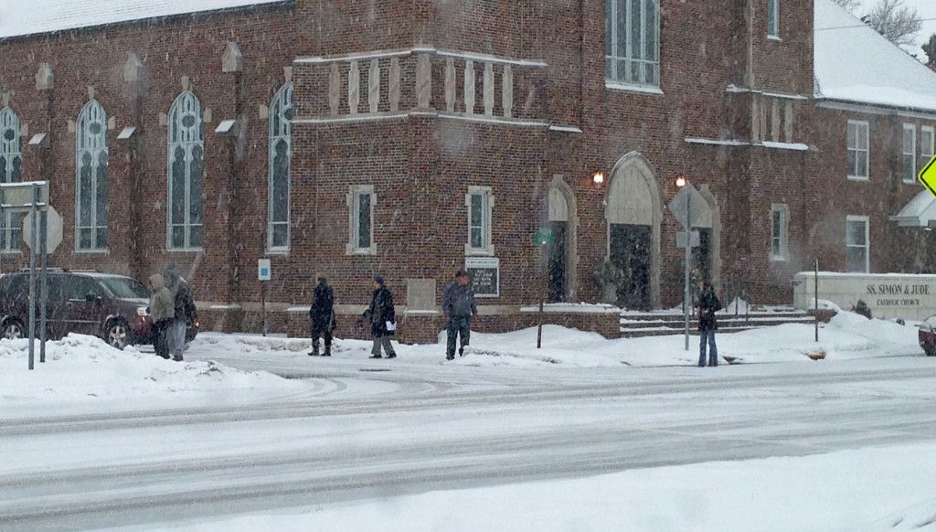Snow starts to fall as people leave mass Saturday afternoon at Saint Simon & Jude in Gillespie.