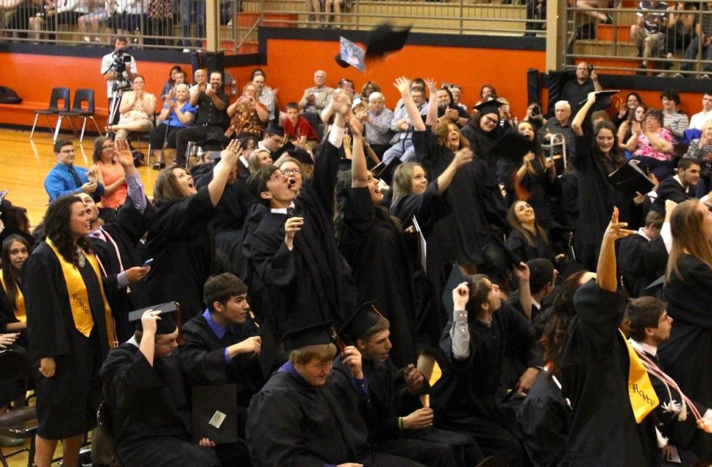 The graduating class tosses their caps into the air.