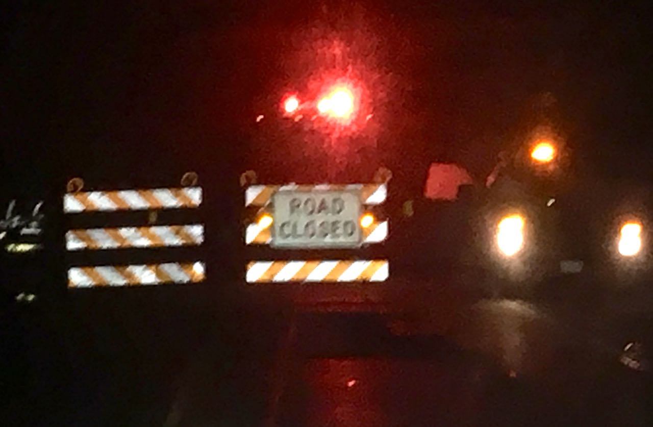 Road closure barricades and first responder vehicles line Illinois Route 16 at Red School Road